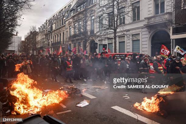 Protestors walk next to a fire during a demonstration, a week after the government pushed a pensions reform through parliament without a vote, using...