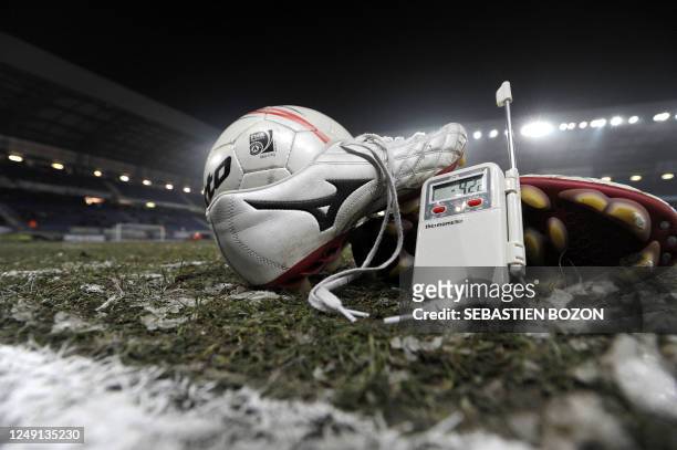 Picture taken on January 10, 2009 in Montbeliard shows a pair of shoes, a ball and a thermometer reading -4,2°C on the field of the Bonnal stadium...