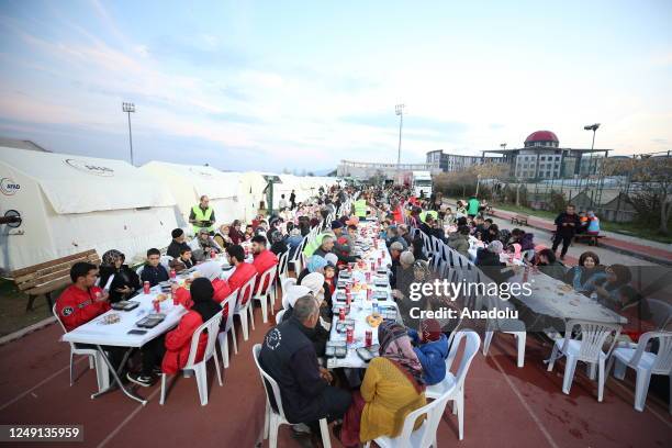 People affected by earthquakes gather for the first iftar dinner of the holy month of Ramadan at a tent city in Kahramanmaras, Turkiye on March 23,...