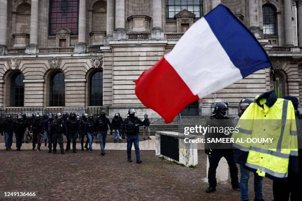 Police officers and French gendarmes near a yellow vest at Place de la Republique during a demonstration, a week after the government pushed a...