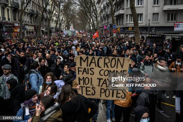 Protester holds a banner reading 'Macron do what I do, tax your friends' during a demonstration, a week after the government pushed a pensions reform...