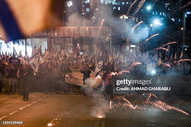 Fireworks explodes before protesters marching in a demonstration against the Israeli government's proposed judicial reform legislation in the central...