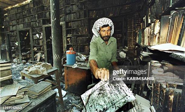 An Iraqi collect the remains of burned books 29 August 1999 at one of Baghdad's main library that caught fire 23 August 1999. Tens of thousands of...