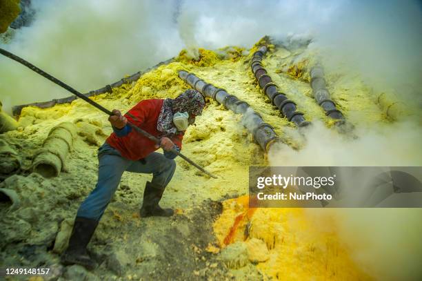 Miner seen surrounded by clouds during compulated the sulfur stalactites while working in the crater of the Ijen volcano in East Java, Indonesia....