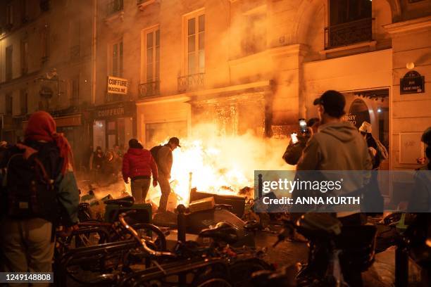 Two men try to remove objects from a fire of rubbish during a demonstration, a week after the government pushed a pensions reform through parliament...