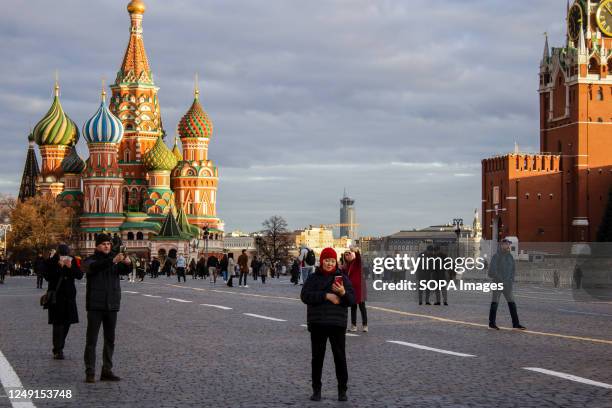 People take pictures on the Red Square with Saint Basil's Cathedral in the background.