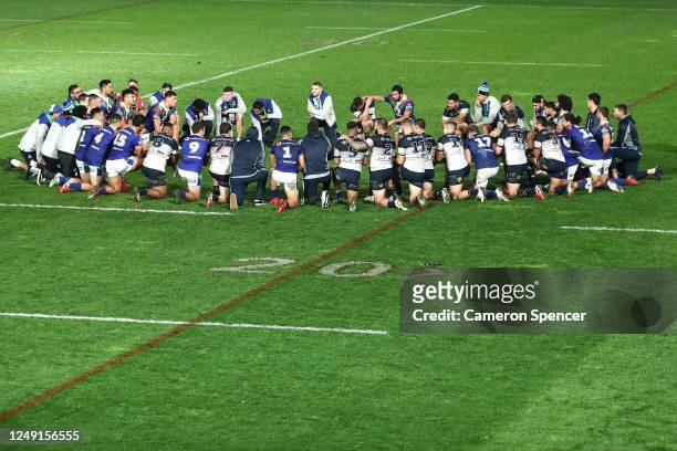 Players from both teams take a knee and huddle together following the round five NRL match between the New Zealand Warriors and the North Queensland...