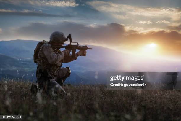 silhouette eines knienden soldaten bei sonnenuntergang - terrorbekämpfung stock-fotos und bilder