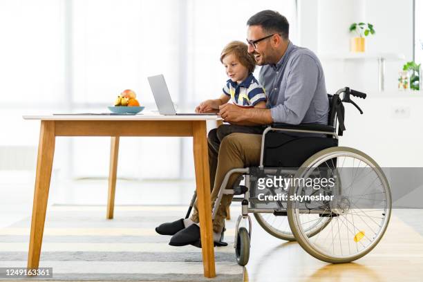 happy disabled father and his small boy using computer at home. - disabled accessibility stock pictures, royalty-free photos & images