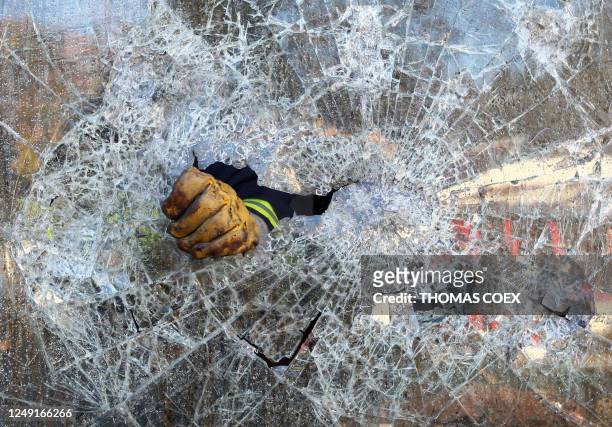 Firefighter removes a broken window in a library near a school, 27 November 2007 in Villiers-le-Bel, outside Paris, after it was torched by rioters...