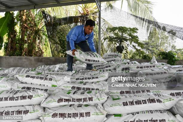 This photo taken on February 27, 2023 shows farmer Dong Van Canh arranging bags of fertilizer at his house in Can Tho. - Rice -- Asia's principal...