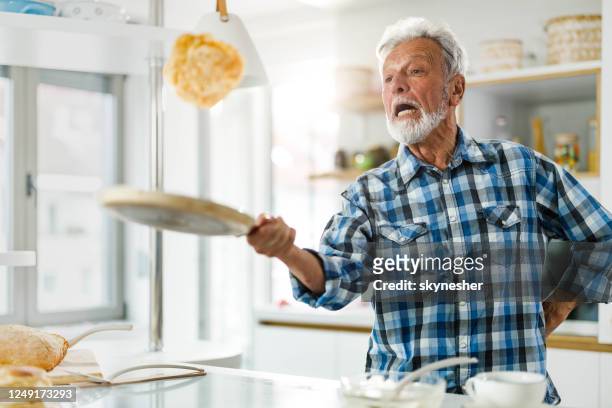 homme aîné ayant l’amusement tout en faisant des crêpes dans la cuisine. - crêpe pancake photos et images de collection