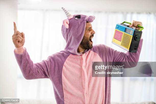 playful man in unicorn costume singing along with radio music. - unicorn stock pictures, royalty-free photos & images