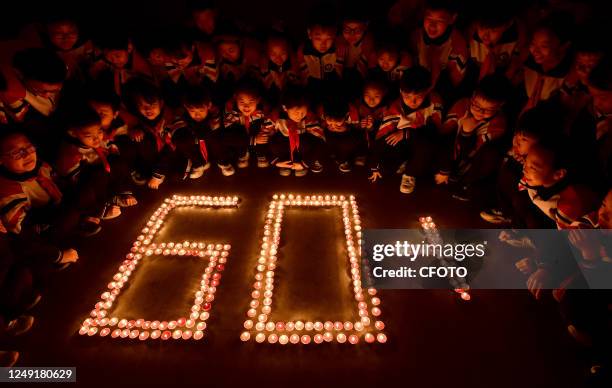 Primary school students use candles to form the characters "60" in Handan, Hebei province, March 24, 2023. The theme of this year's Earth Hour is...