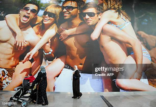 Customers pass by a giant advertsing billboard at the newly opened Westfield Stratford City shopping centre in east London, on September 13, 2011....