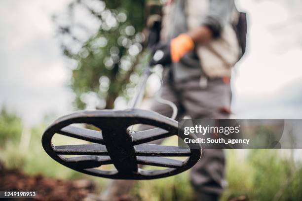 mens op een schatjacht met een metaaldetector op het gebied - schatzoeken stockfoto's en -beelden
