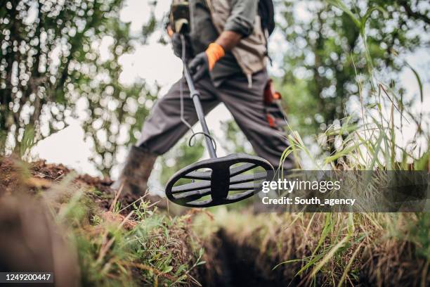 senior man on a treasure hunt with a metal detector in the nature - treasure hunt stock pictures, royalty-free photos & images