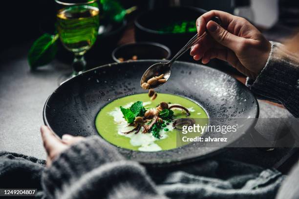 close-up of woman garnishing green peas and cream soup - soup on spoon stock pictures, royalty-free photos & images