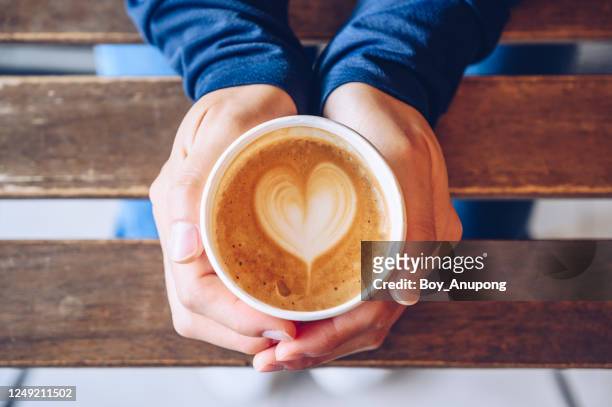 high angle view of someone hands holding a take away cup of hot latte coffee. - coffee heart stock pictures, royalty-free photos & images