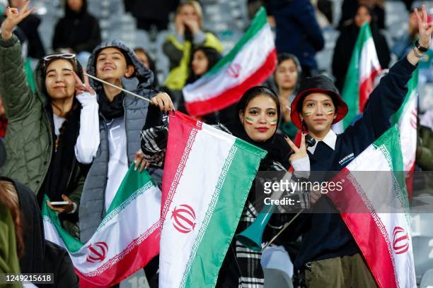 Women football fans wave Iranian national flags as they cheer for their national team during the friendly football match between Iran and Russia at...