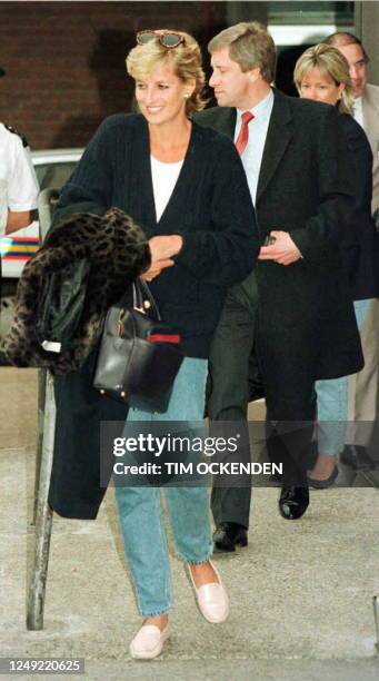 Princess Diana is escorted out of Heathrow Airport by an unidentified man 04 January upon her return form a one-week holiday on the Caribbean island...