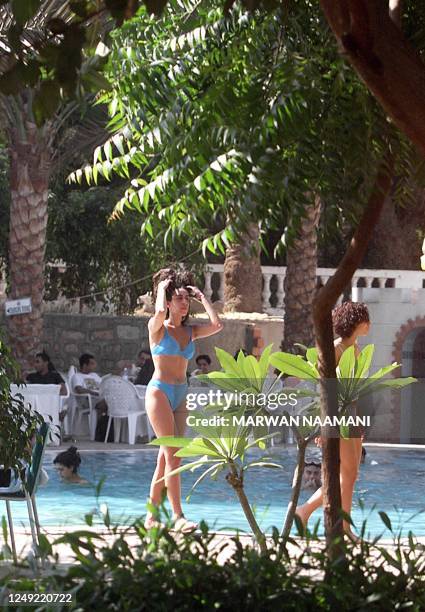 An Egyptian girl fixes her hair as she passes the swimming pool of the Royal Mohammad Ali Club in the outskirts of Cairo, which was packed 01 October...