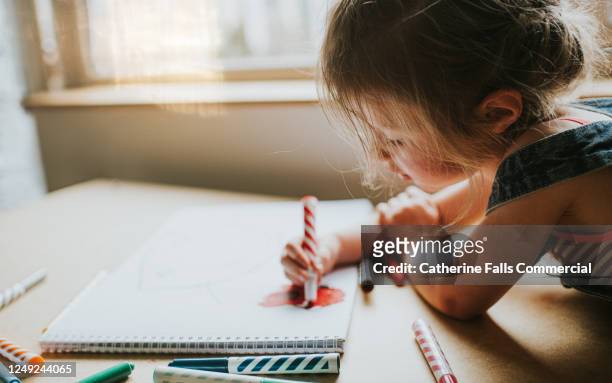little girl drawing in a big sketch book with felt tips - ligga på mage bildbanksfoton och bilder