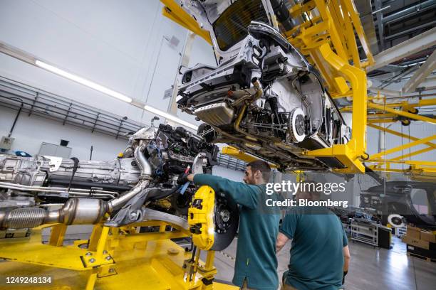 Employees prepare to marry the engine to the chassis of an Aston Martin DBX sport utility vehicle on the final assembly line at the Aston Martin...