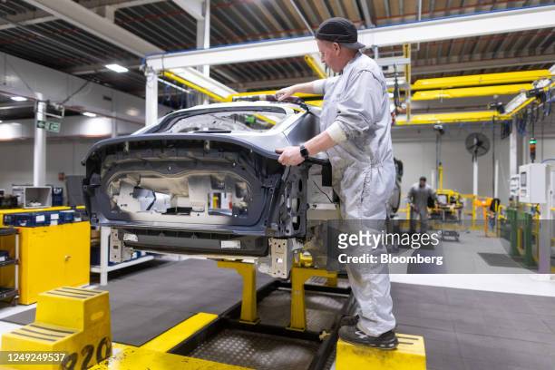 An employee measures gaps between sections of bodywork on an Aston Martin DBX sport utility vehicle in the bodyshop at the Aston Martin Lagonda...