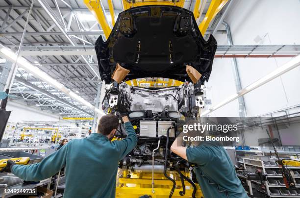 Employees fix an engine unit to the chassis of an Aston Martin DBX sport utility vehicle on the final assembly line at the Aston Martin Lagonda...