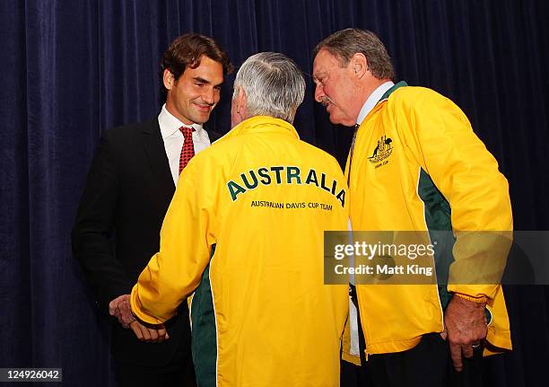 Roger Federer and former Australian tennis players Ken Rosewall and John Newcombe shake hands on stage during the official dinner ahead of the Davis...