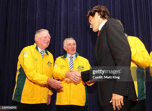 Roger Federer and former Australian tennis players Frank Sedgman and Ken Rosewall shake hands on stage during the official dinner ahead of the Davis...