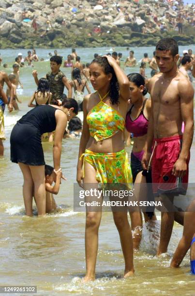 Young Moroccan looks at a girl in bathing suit as others enjoy sun bathing on the beach in Rabat, 04 July 2004. A sermon by Imam Redouane...