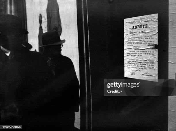 Photo prise au lendemain du 06 février 1934 à Paris de Parisiens découvrant l'arrêté du préfet de police d'interdiction de rassemblement sur la voie...