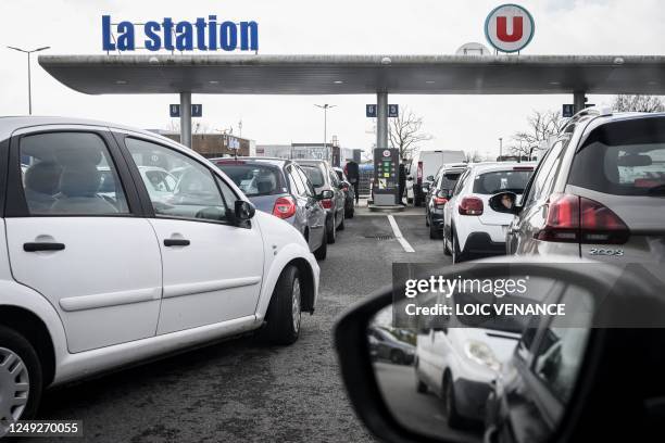 People queue to fill their cars with fuel at a service station in Savenay, on March 24, 2023. - Protesters have blockaded oil refineries after the...