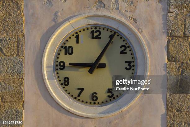 Clock is seen on a church bell tower in L'Aquila, Italy, on March 24, 2023. On march 26th solar time will replace daylight saving time and people...