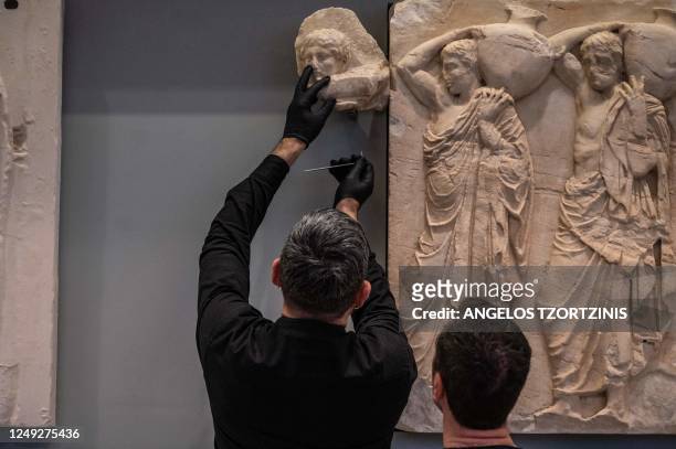Curator holds one of three fragments of the Parthenon, during a ceremony at the Acropolis Museum in Athens on March 24, 2023. - Pope Francis returned...