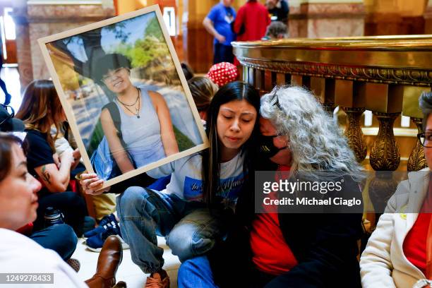 Selma Martinez hugs Lynne Valencia-Hernandez while holding a photo of her sister, Alaina Martinez, who was a high school senior and was killed in a...