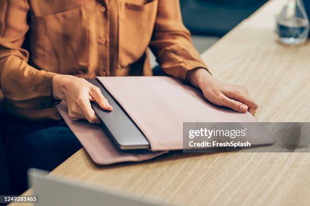 handen van een onderneemster die haar computer van laptop uit de koker op haar bureau neemt - mouw stockfoto's en -beelden