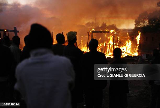 Local residents watch shacks burning on May 25, 2008 as firefighters attempt to extinguish it in Denver squatter camp on the outskirts of...