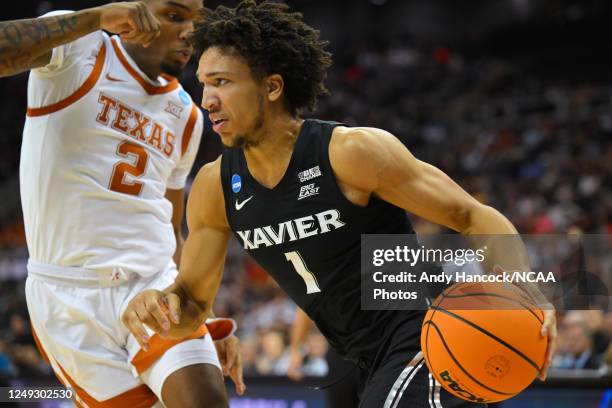 Guard Desmond Claude of the Xavier Musketeers dribbles the all past guard Arterio Morris of the Texas Longhorns during the Sweet Sixteen round of the...