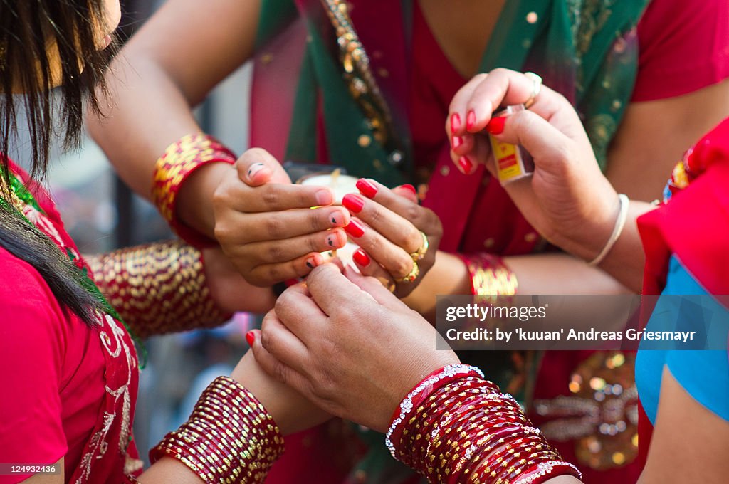 Hindu ladies painted hands for Teej light candle