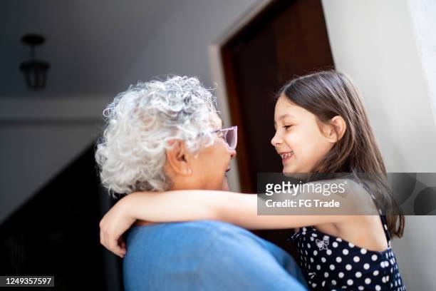 grandmother and granddaughter embracing at home - granddaughter stock pictures, royalty-free photos & images