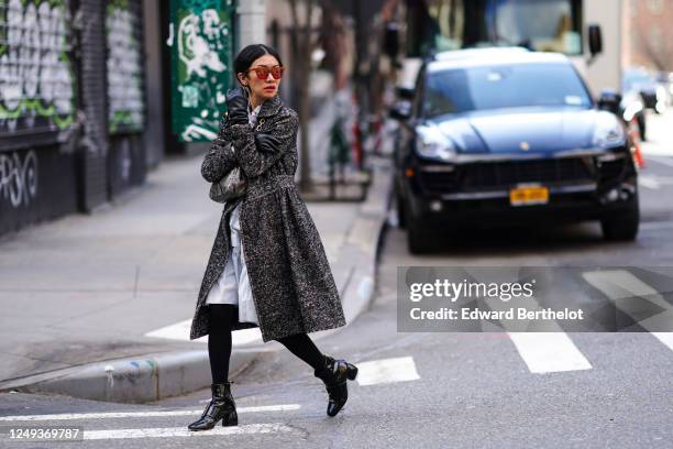 Guest wears red sunglasses, black leather gloves, a gray striped wool coat, a leather snake print bag, a white long ruffled dress, black leggings,...