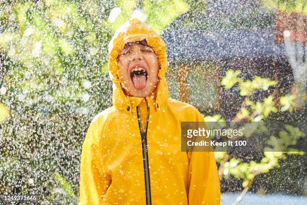 happy child enjoying the rain - raincoat stock pictures, royalty-free photos & images