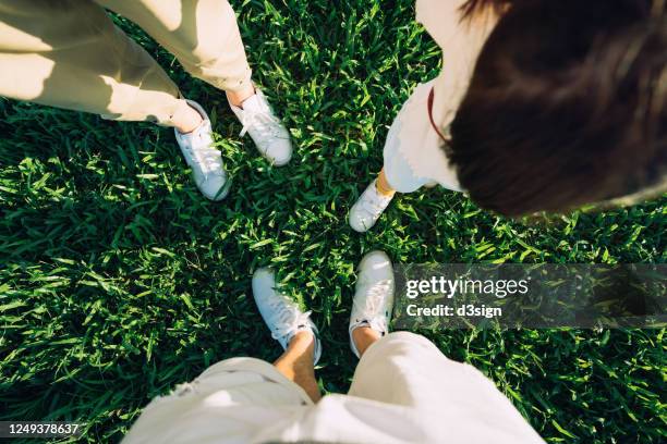 subject view of the low section of a loving asian family of three holding hands on a meadow with beautiful sunlight illuminated on them - feet selfie woman stockfoto's en -beelden