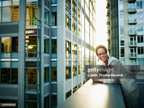 businesswoman leaning on edge of deck smiling - portrait outdoor business foto e immagini stock