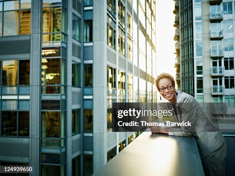 Businesswoman leaning on edge of deck smiling