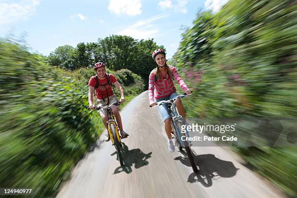 young couple cycling in country lane - bicycle lane stock-fotos und bilder