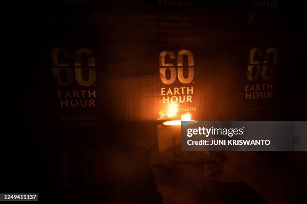 An Indonesian activist lights a candle during the Earth Hour environmental campaign in Surabaya on March 25, 2023.